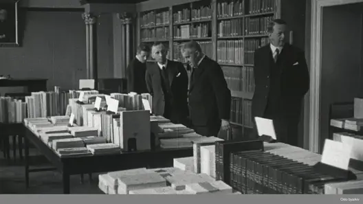 Personer fra Universitetsbiblioteket tar i mot bøker i gave fra personer fra Frankrike.
